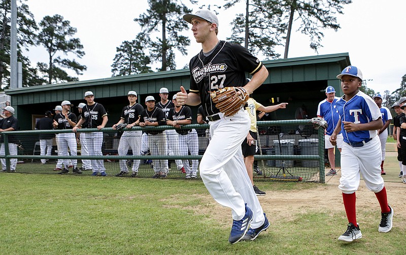 Texarkana Twins third baseman Brian Hamilton runs onto the field with a player from the Texarkana, Texas, Dixie Youth 12 Rangers before the Twins' game against the Baton Rouge Rougarous.
