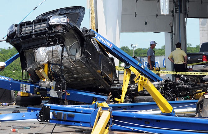 Workers at Riley Chevrolet continue to assess damage to building and cars Friday.
