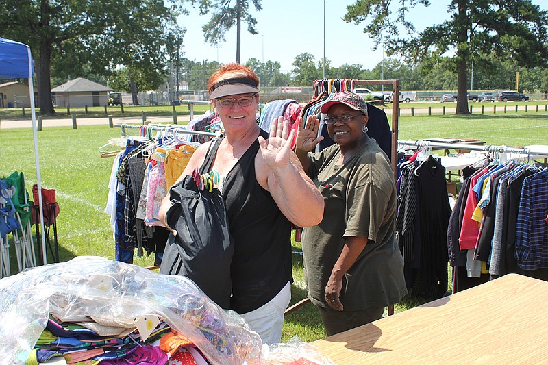 Smiling shoppers in search of bargains peruse merchandise on a hot Saturday afternoon at Spring Lake Park. 
