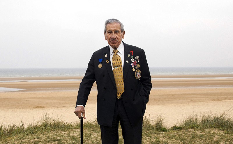 In this May 1, 2019, photo, World War II and D-Day veteran Charles Norman Shay, from Indian Island, Maine, poses on a dune at Omaha Beach in Saint-Laurent-sur-Mer, Normandy, France. Shay was a medic who on June 6, 1944, landed on Omaha Beach, where he helped drag wounded soldiers out of the rising tide, saving them from drowning. For his courage, he was awarded the Silver Star. (AP Photo/Virginia Mayo)