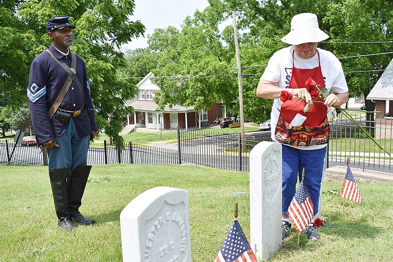 At right, Jeanne Rutledge of the city's Cemetery Resources Board places flowers in front of the new headstones for 13 recently identified Civil War soldiers buried at Woodland-Old City Cemetery. They were among 750 Civil War soldiers buried there without grave markers. At left, Lincoln University professor Essex Garner stands at attention wearing a Civil War uniform.