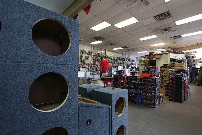 A customer asks about kickers to be installed in his car May 28 at Almost Everything Inc. in Texarkana, Texas. The business is closing after 25 years and the owners are retiring. 