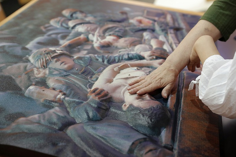 Norma Crosby, state president for the Texas chapter of the National Federation of the Blind, and Sophie Trist, right, a New Orleans chapter member, touch a bass relief of a photograph of the Vietnam Tet Offensive, by John Olson, whose company 3DPhotoworks also makes the bass relief, at the American Alliance of Museums Expo in New Orleans, Monday, May 20, 2019. It is one example of how museums are reaching out to make their collections more accessible, said Elizabeth Merritt, vice president for strategic foresight for the group, which represents museums of all sorts, from tiny community history museums to huge zoos. (AP Photo/Gerald Herbert)