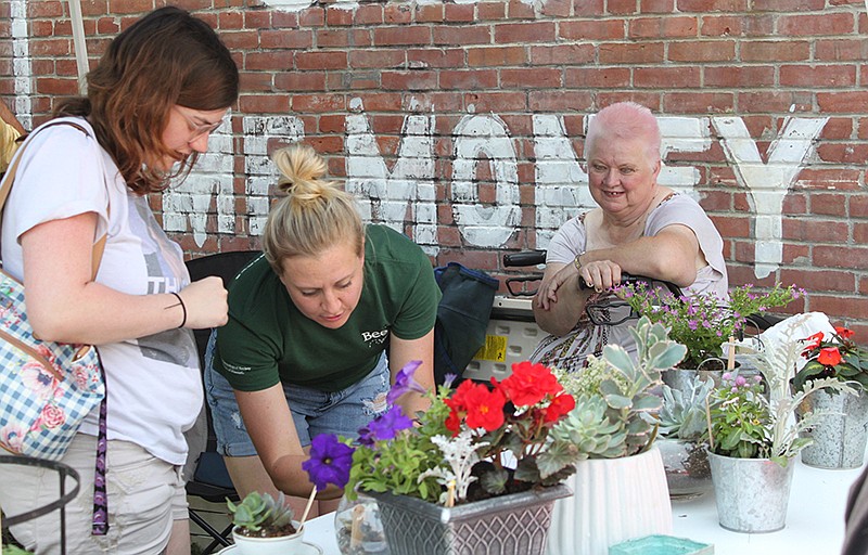 Rachel Irey, right, introduces Jade Perez, left, to a floral selection of succulents and other plants Irey sold at the June 1, 2019, Oak Street Farmer's Market.