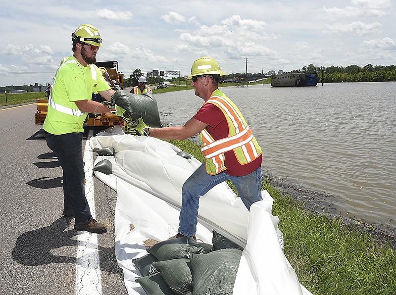 Grant Kleindienst, left, hands a sandbag to Micah Lasley to form an 18-inch-plus wall at the U.S. 63 exit ramp to U.S. 54 in north Jefferson City to fortify the curve in an effort to prevent the flood water from encroaching on the highway ramp. They both work for MoDOT's Central District and were part of a larger crew who were working June 5, 2019, to stave off the rising water.