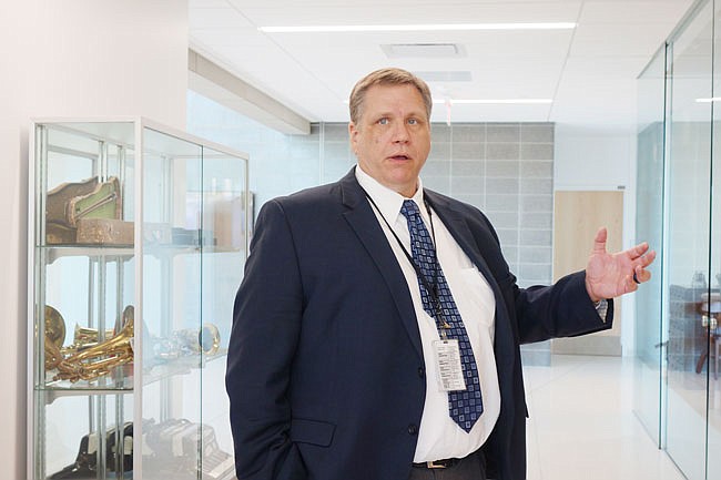 Andy Atkinson, Chief Operating Officer of the Fulton State Hospital, gestures toward a display of historical artifacts from the former FSH building. The hospital was established in 1851 and the display reflects that history in the new Nixon Forensic Center.