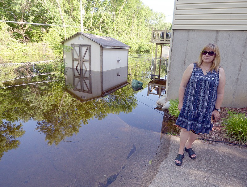 Lois Hogan checks on the rising floodwaters Wednesday at her property located at 1006 Geneva St. The property was recently sold.