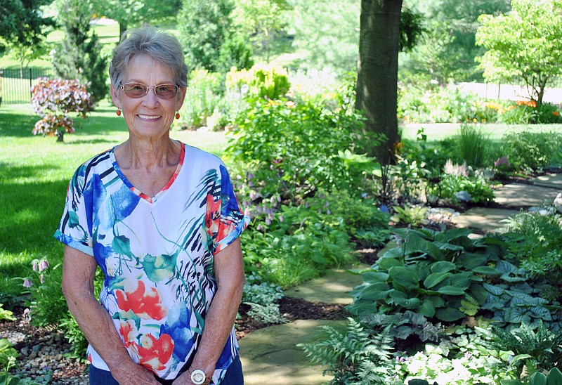 <p>(Photo by Samantha Pogue) Merrilee Holzhouser stands in her backyard, which is an oasis of colorful flowers, plants, yard art and more and has earned her the Bittersweet Garden Club’s May Garden of the Month.</p>