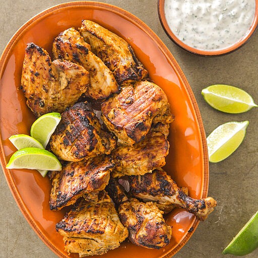 This undated photo provided by America's Test Kitchen in May 2019 shows Tandoori Chicken with Raita in Brookline, Mass. This recipe appears in the cookbook "Spiced.” (Joe Keller/America's Test Kitchen via AP)