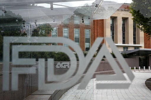 FILE - This Thursday, Aug. 2, 2018, file photo shows the U.S. Food and Drug Administration building behind FDA logos at a bus stop on the agency's campus in Silver Spring, Md. The Food and Drug Administration’s first broad testing of food for a worrisome class of nonstick, stain-resistant industrial compounds found high levels in some grocery store meats and seafood and in off-the-shelf chocolate cake, according to unreleased findings FDA researchers presented at a scientific conference in Europe. (AP Photo/Jacquelyn Martin, File)