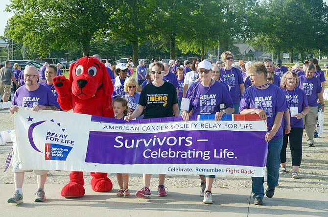 Surrounded by family, cancer survivor Andi Schulte, 7, walks alongside Clifford during the first lap of the 2019 Cole County Relay for Life on Friday, June 7, 2019, at the Jefferson City Jaycees Fairgrounds.
