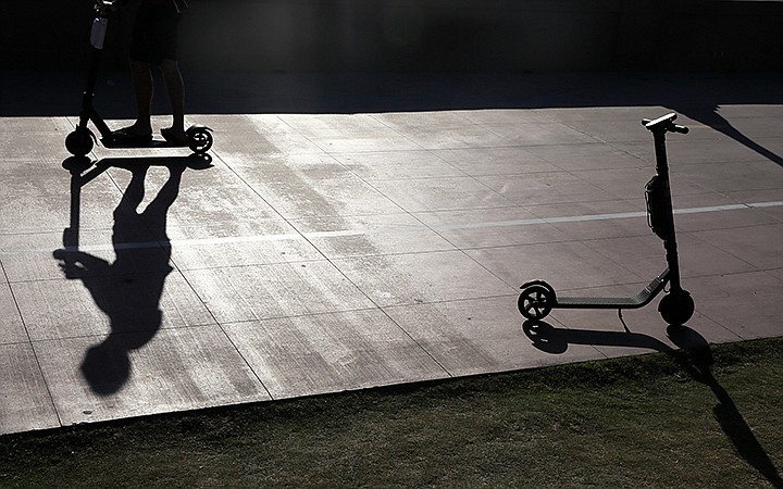  In this May 28, 2019, file photo, a man on a scooter passes a parked scooter along the Mission Beach boardwalk in San Diego. As electric scooters have rolled into more than 100 cities worldwide, many of the people riding them have ended up in the emergency room with serious injuries. Others have been killed.  (AP Photo/Gregory Bull, File)