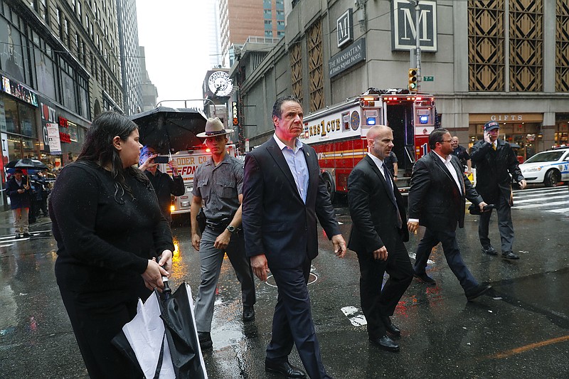 New York Gov. Andrew Cuomo, center, walks near the scene where a helicopter was reported to have crash-landed on top of a building in midtown Manhattan, Monday, June 10, 2019, in New York.  (AP Photo/Mark Lennihan)