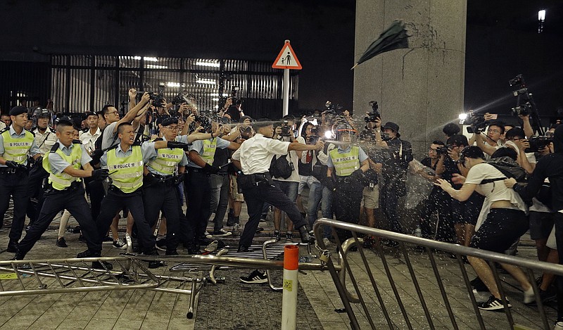 Police officers use pepper spray against protesters in a rally against the proposed amendments to the extradition law at the Legislative Council in Hong Kong during the early hours of Monday, June 10, 2019. The extradition law has aroused concerns that this legislation would undermine the city's independent judicial system as it allows Hong Kong to hand over fugitives to the jurisdictions that the city doesn't currently have an extradition agreement with, including mainland China, where a fair trial might not be guaranteed. (AP Photo/Vincent Yu)