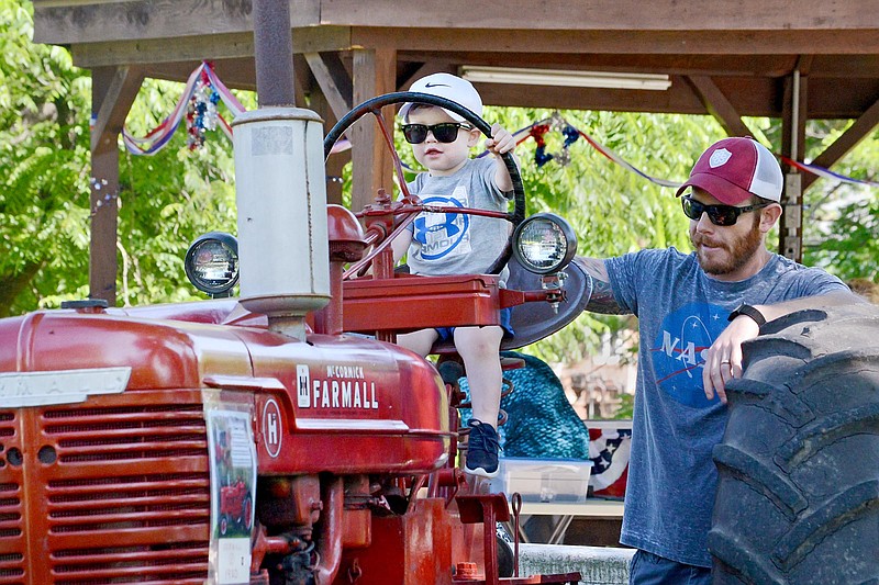 Hugh Wilson, 1, of Jefferson City, plays on a tractor next to his dad, Chris, Saturday June 8, 2019, during the Russellville Engine Show and Festival. The three-day event is a celebration of the founding of the city, which formed in 1838. It also featured several vendors, a parade, a classic car show and a variety of activities for children.