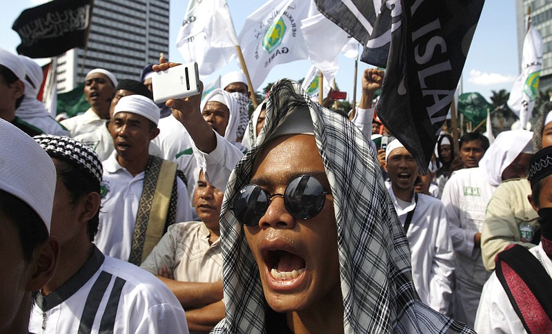 FILE - In this May 3, 2013, file photo, members of the militant Islamic Defenders Front (FPI) shout slogan during a demonstration in Jakarta, Indonesia. The Islamic Defenders Front, better known for vigilante actions against gays, Christmas decorations and prostitution, has over the past decade and a half repurposed its militia into a force that's as adept at searching for victims buried under earthquake rubble and distributing aid as it is at inspiring fear. (AP Photo/Achmad Ibrahim, File)