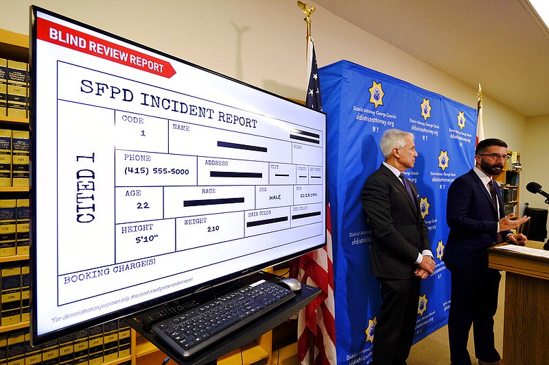 With a blind police incident report displayed, San Francisco District Attorney George Gascon, left, and Alex Chohlas-Wood, Deputy Director, Stanford Computational Policy Lab, talk about the implementation of an artificial intelligence tool to remove potential for bias in charging decisions, during a news conference Wednesday, June 12, 2019, in San Francisco. In a first-of-its kind experiment, San Francisco prosecutors are turning to artificial intelligence to reduce bias in the criminal courts.