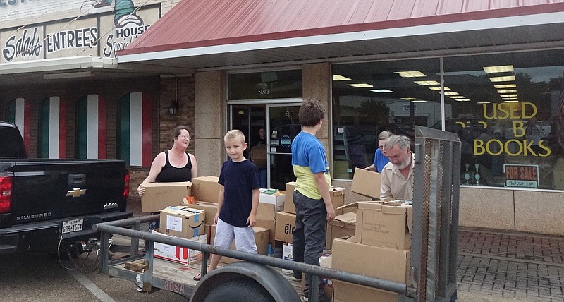 Laura Comer, left, and Eugene Comer load a trailer with boxes of books, along with the help of Eli Smith and Isaac Harwell.