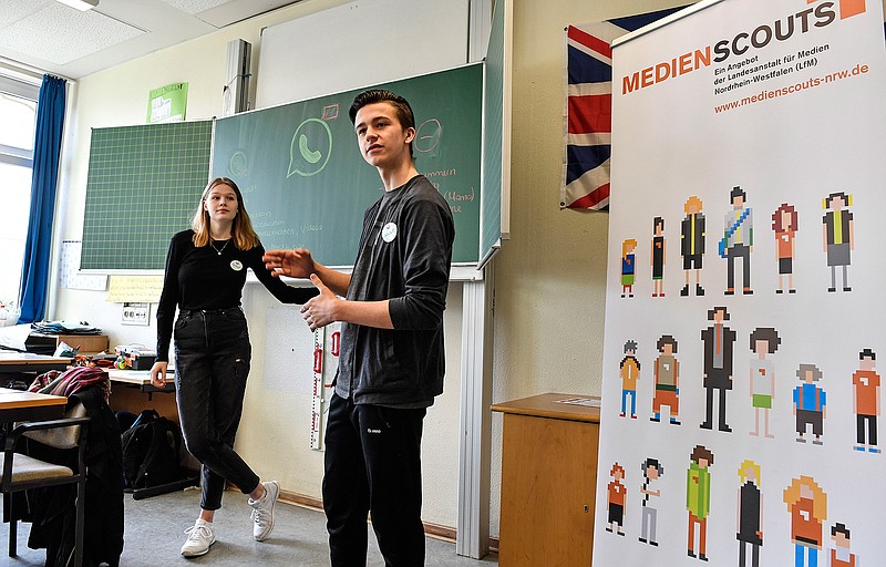 Senior students and media scouts Leon Zielinski, right, and Chantal Hueben teach young pupils during a lesson in social media and internet at a comprehensive school in Essen, Germany, Monday, March 18, 2019. According to experts and teachers the peer projects in which teenagers teach their younger schoolmates how to stay safe and sane online have proven to be especially successful.  (AP Photo/Martin Meissner)