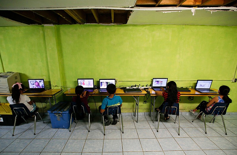 Migrant children watch laptops inside the Agape World Mission shelter used mostly by Mexican and Central American migrants who are applying for asylum in the U.S., on the border in Tijuana, Mexico, Monday, June 10, 2019. (AP Photo/Eduardo Verdugo)