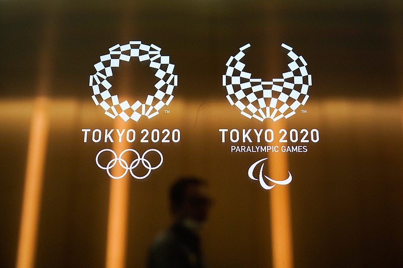 A man walks past the Tokyo 2020 Olympic logos Tuesday, June 11, 2019, in Tokyo. Earlier, Tokyo Olympic organizers announced their gold, silver, and bronze medals would be made of discarded electronic devises. Now, they are going a step further. The podiums that athletes will mount to receive their medals next year in Tokyo will be made primarily of recycled household plastics.(AP Photo/Jae C. Hong)