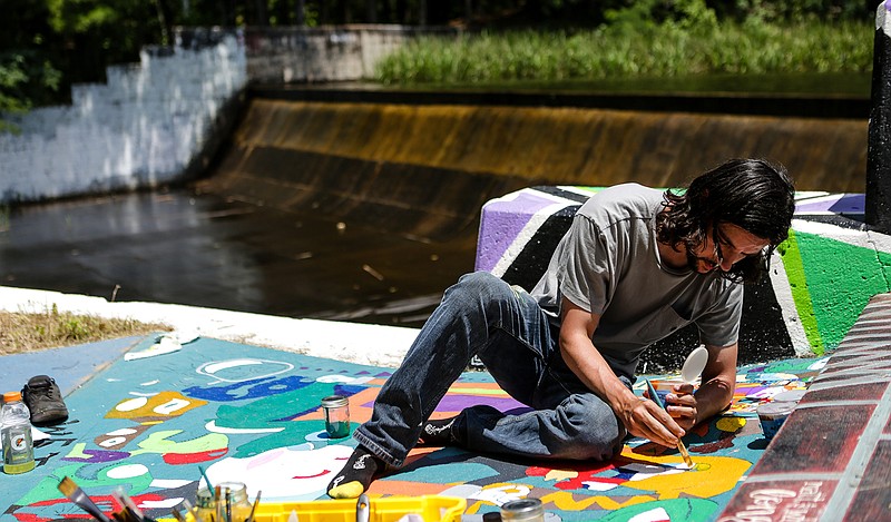 Dugan Livingston paints his collage of characters Tuesday at the Bringle Lake dam path in Texarkana, Texas. Livingston has been working on his piece for the past three days, spending eight hours or more a day to finish his piece.