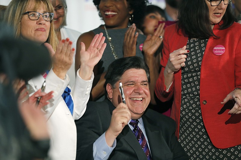 Illinois Gov. J.B. Pritzker signs the Reproductive Health Act into law with bill sponsors Illinois State Senator Melinda Bush, left, and Illinois State Rep. Kelly Cassidy, right, at the Chicago Cultural Center on Wednesday,  June 12, 2019. The law establishes "the fundamental right" of a pregnant woman to have an abortion and states that "a fertilized egg, embryo, or fetus does not have independent rights." (Jose M. Osorio/Chicago Tribune via AP)