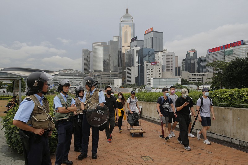 Riot police stand guard as protesters walk outside the Legislative Council in Hong Kong, Thursday, June 13, 2019. After days of silence, Chinese state media is characterizing the largely peaceful demonstrations in Hong Kong as a "riot" and accusing protesters of "violent acts." (AP Photo/Kin Cheung)