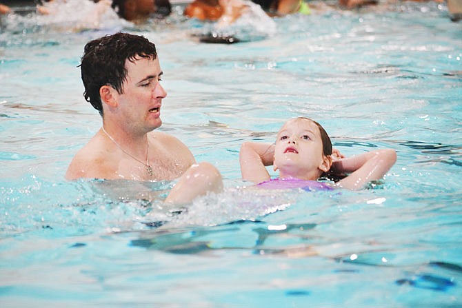 Jefferson City firefighter Jordan Holland assists Brylee McComas with a water safety technique Tuesday during a second-graders swim/water safety class at the Knowles YMCA. 