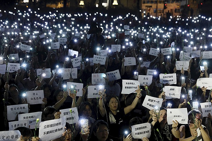 Hundreds of mothers holding placards, some of which read "If we lose the young generation, what's left of Hong Kong", and lit smartphones protest against the amendments to the extradition law in Hong Kong on Friday, June 14, 2019. Calm appeared to have returned to Hong Kong after days of protests by students and human rights activists opposed to a bill that would allow suspects to be tried in mainland Chinese courts. (AP Photo/Vincent Yu)