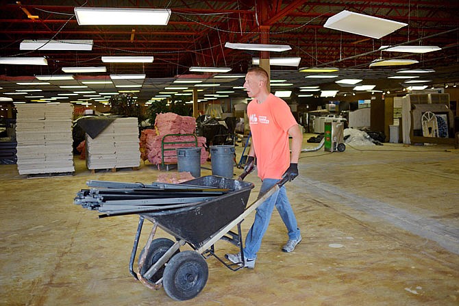 Showroom manager Jim Mays removes ceiling tile tracks inside the showroom at Missouri Furniture, which was heavily damaged in the May 22 tornado. 