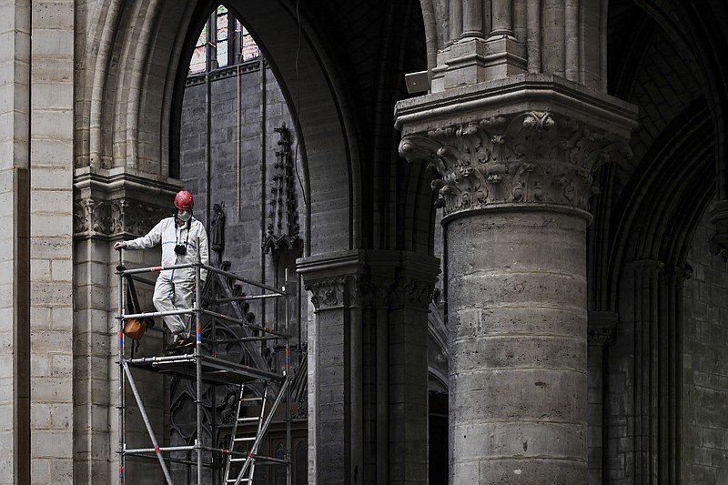 FILE - In this May 15, 2019 file photo, a worker stands on scaffolding during preliminary work inside the Notre Dame de Paris Cathedral, in Paris.  The billionaire French donors that publicly promised flashy donations totalling hundreds of millions to restore Notre Dame, have not yet paid a penny toward the restoration of the French national monument, according to church and business officials. Instead, it's mainly American citizens that have footed the bills and paid salaries for the up to 150 workers employed by the cathedral since the April 15 fire. (Philippe Lopez/Pool via AP, File)