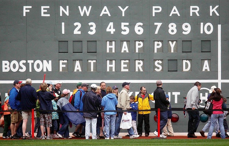 FILE - In this June 21, 2009 file photo, fans tour in front of the scoreboard in Fenway Park in Boston in celebration of Father's Day following a baseball game between the Atlanta Braves and the Boston Red Sox. The U.S. Census Bureau has released a new report showing more than 60% of the 121 million men in the U.S. are fathers. The data in the report released this week of June 15, 2019, comes from 2014 when the bureau for the first time asked both men and women about their fertility histories. The report says just under three-quarters of fathers are married. Almost 13% of dads are divorced and 8% have never been married.  (AP Photo/Michael Dwyer)