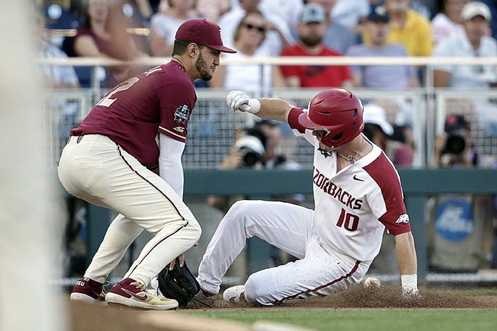 Arkansas' Matt Goodheart (10) is safe at third base ahead of the throw to Florida State third baseman Drew Mendoza on a base hit by Dominic Fletcher in the sixth inning of an NCAA College World Series baseball game in Omaha, Neb., Saturday, June 15, 2019. (AP Photo/Nati Harnik)