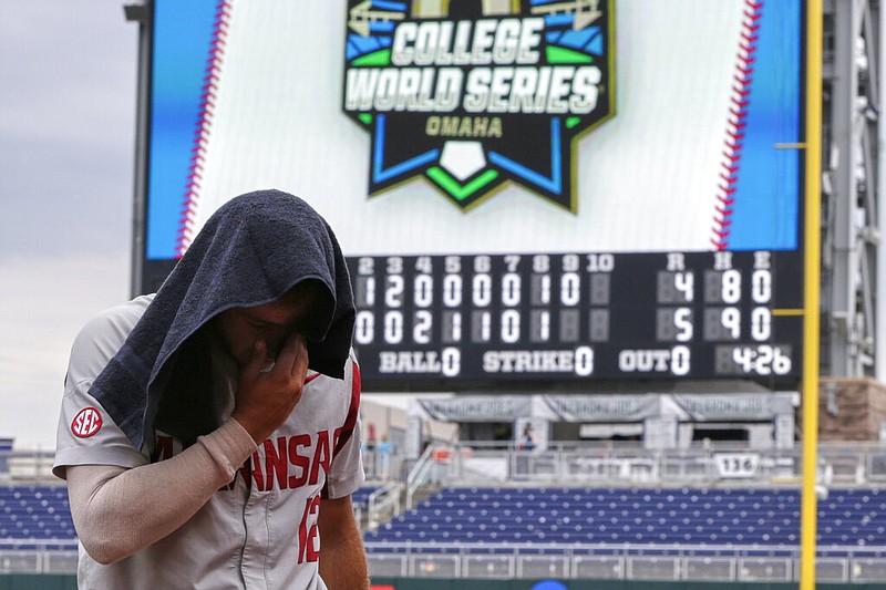 Arkansas catcher Casey Opitz (12) covers his head as he walks off the field following an NCAA College World Series baseball game against Texas Tech in Omaha, Neb., Monday, June 17, 2019.