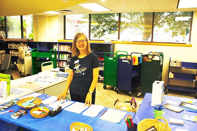 Callaway County Public Library children's librarian Jerilyn Hahn stands by the informational table on the various summer reading programs. This theme for Daniel Boone Regional Library's summer reading program is "a universe of stories."