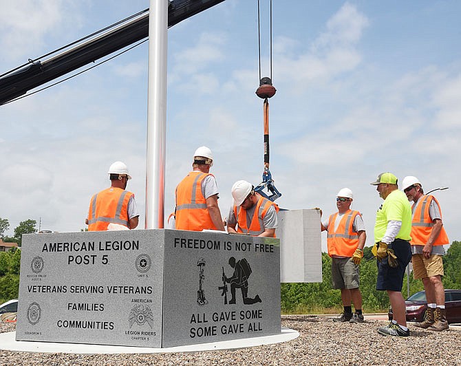 Employees of Midwest Block and Brick work on the pentagon-shaped memorial Tuesday at the base of a 40-foot-tall flag pole in the roundabout on Supercenter Drive on the city's east end.