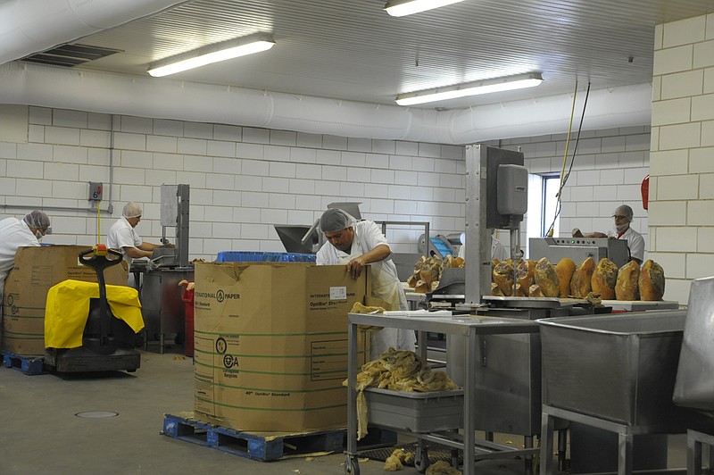 Inside Burgers' Smokehouse near California, employees work to process country cured hams and a variety of other meats. (June 2019 photo)