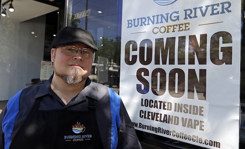 Johnny Rowan stands outside Burning River Coffee, Friday, June 14, 2019, in Lakewood, Ohio. Rowan’s is one of 90 active businesses registered with the state that have “burning river” in their names, inspired by the Cuyahoga River’s most famous fire. (AP Photo/Tony Dejak)