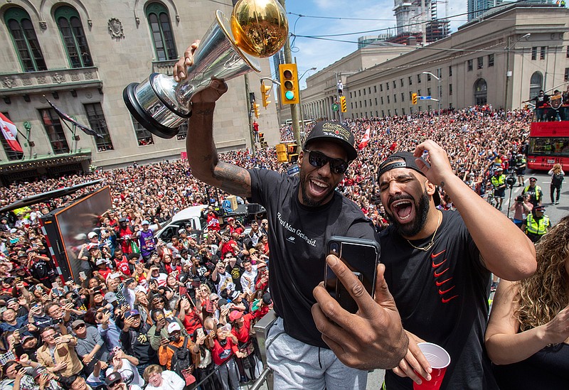 Toronto Raptors' Kawhi Leonard holds his MVP trophy while celebrating with rapper/producer Drake during the team's NBA basketball championship parade in Toronto, Monday, June 17, 2019. (Frank Gunn/The Canadian Press via AP)