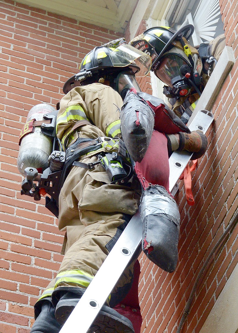 The Jefferson City Fire Department goes through fire and rescue training Wednesday at a vacant house on Swifts Highway. The department performed 'rescues' of mannequins from the second floor.