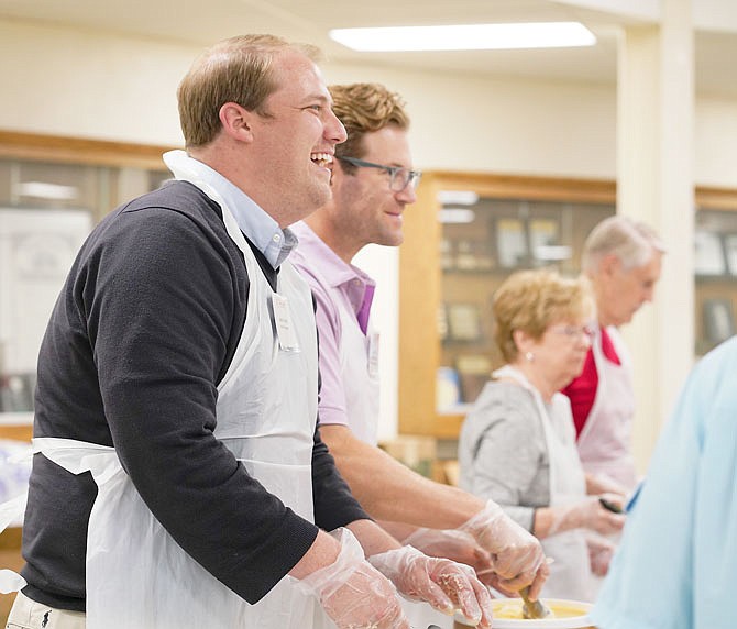 Celebrity servers Andy Fechtel, near, and Jake Vogel dish out a smile with the ice cream Wednesday during the 62nd annual St. Mary's Ice Cream Social at the undercroft of the Cathedral of St. Joseph, where it's been held for the last decade. The number of people served lunch or supper was estimated to be around 1,200. The annual event features celebrity ice cream servers that range from local elected officials to active community leaders, as seen here, who each spent about an hour serving up local favorite Central Dairy ice cream. 