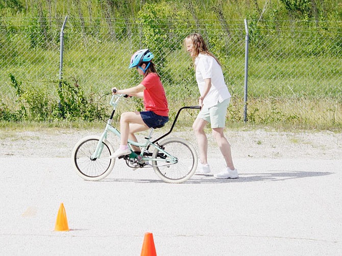 Volunteer Gina Mackenzie helps camper Julianna Basi gain stability on a bike as she nears the final stages of the camp. Basi is in her fourth year at the Fulton iCan Bike camp.