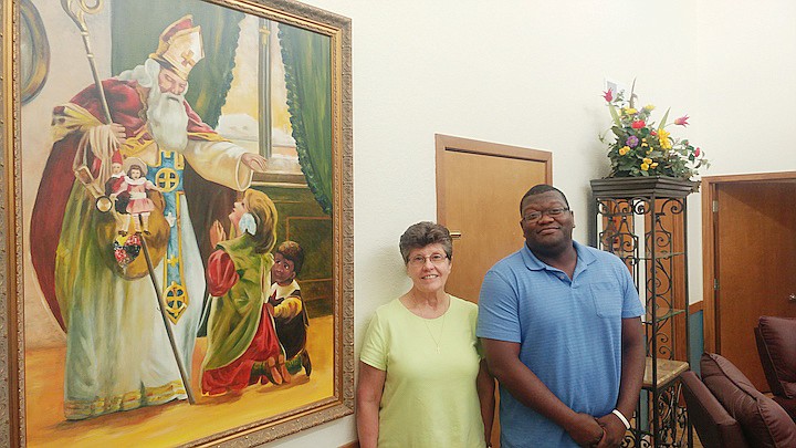 St. Nicholas Academy Director Sister Susan Renner stands inside the boarding school with Funtez Robinson, who will be a live-in house parent for the academy with his wife, Unique. The painting on the wall is of St. Nicholas.