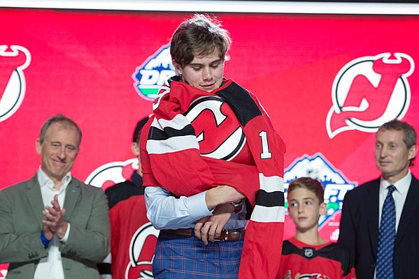 Jack Hughes puts on his Devils jersey Friday night after being the No. 1 overall pick in the NHL draft in Vancouver, British Columbia.