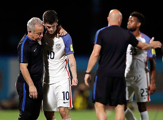 In this Oct. 10, 2017, file photo, Christian Pulisic is comforted by U.S. assistant coach Dave Sarachan after the 2-1 loss to Trinidad and Tobago in 2018 World Cup qualifying.