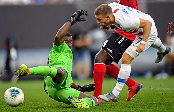 Trinidad and Tobago goalkeeper Marvin Phillip deflects the ball after a shot by U.S. forward Paul Arriola during Saturday night's match in Cleveland.