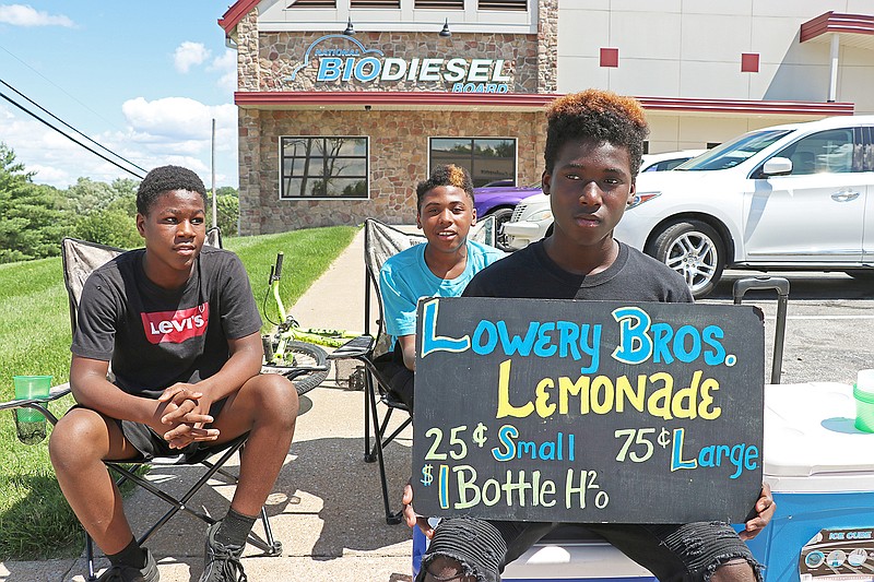 From left, Keith Dixon, 11, Kevin Lowery, 12, and Devonte Lowery, 14, sell lemonade Monday along Clark Avenue. The trio and friends are raising money for new school clothes. They plan to sell lemonade throughout the summer.