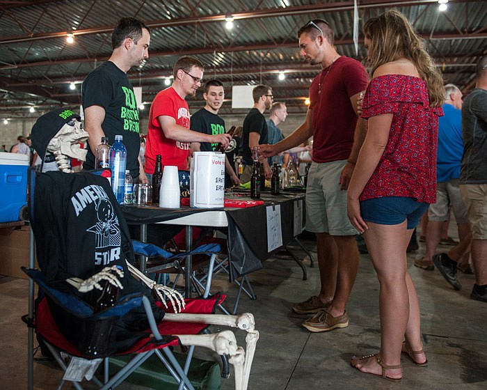 Levi Elder, center right, samples a beer selection from the Boo Brothers Brewery with Monica Katnik, right, during Battle of the Brews at the Jefferson City Jaycee Fairgrounds on Friday, June 8, 2018. Front left to center, Jerry the skeleton, Kris Pruett, Zak Singleton and Grant Sherwood were present to represent Boo Brothers Brewery, a home brewer company from Holts Summit, Missouri, owned by Cody Singleton, not pictured. 