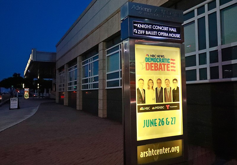 In this June 21, 2019 photo, a sign outside the Knight Concert Hall at the Adrienne Arsht Center for the Performing Arts of Miami-Dade County announces the upcoming Democratic Presidential Debates, in Miami. Democratic presidential hopefuls face a challenge as they gather in Miami this week for the opening round of primary debates: presenting immigration ideas that go beyond simply bashing President Donald Trump's administration. (AP Photo/Wilfredo Lee)
